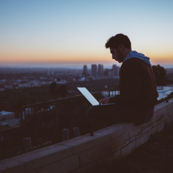 man using laptop outside at dusk